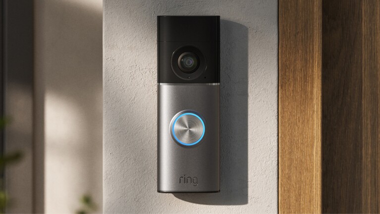 Ring video doorbell mounted on wall next to wooden door frame