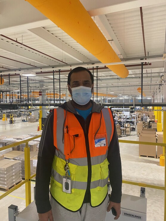 Imtiaz Hussain, stores coordinator, standing in a fulfilment centre wearing a high-vis jacket.
