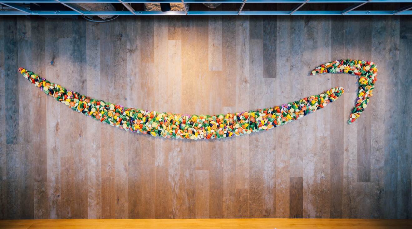 木製の壁にさまざまな色で描かれたAmazonのスマイルロゴ