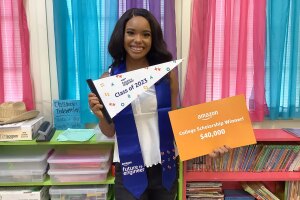 An image of Micah Hill, a 2023 Amazon Future Engineer Scholarship recipient, holding out a sign that reads "Amazon College Scholarship Winner."