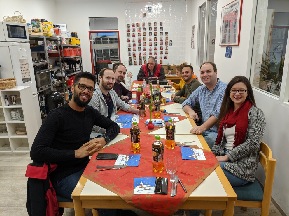 Verschiedene Personen sitzen an einem langen Tisch.