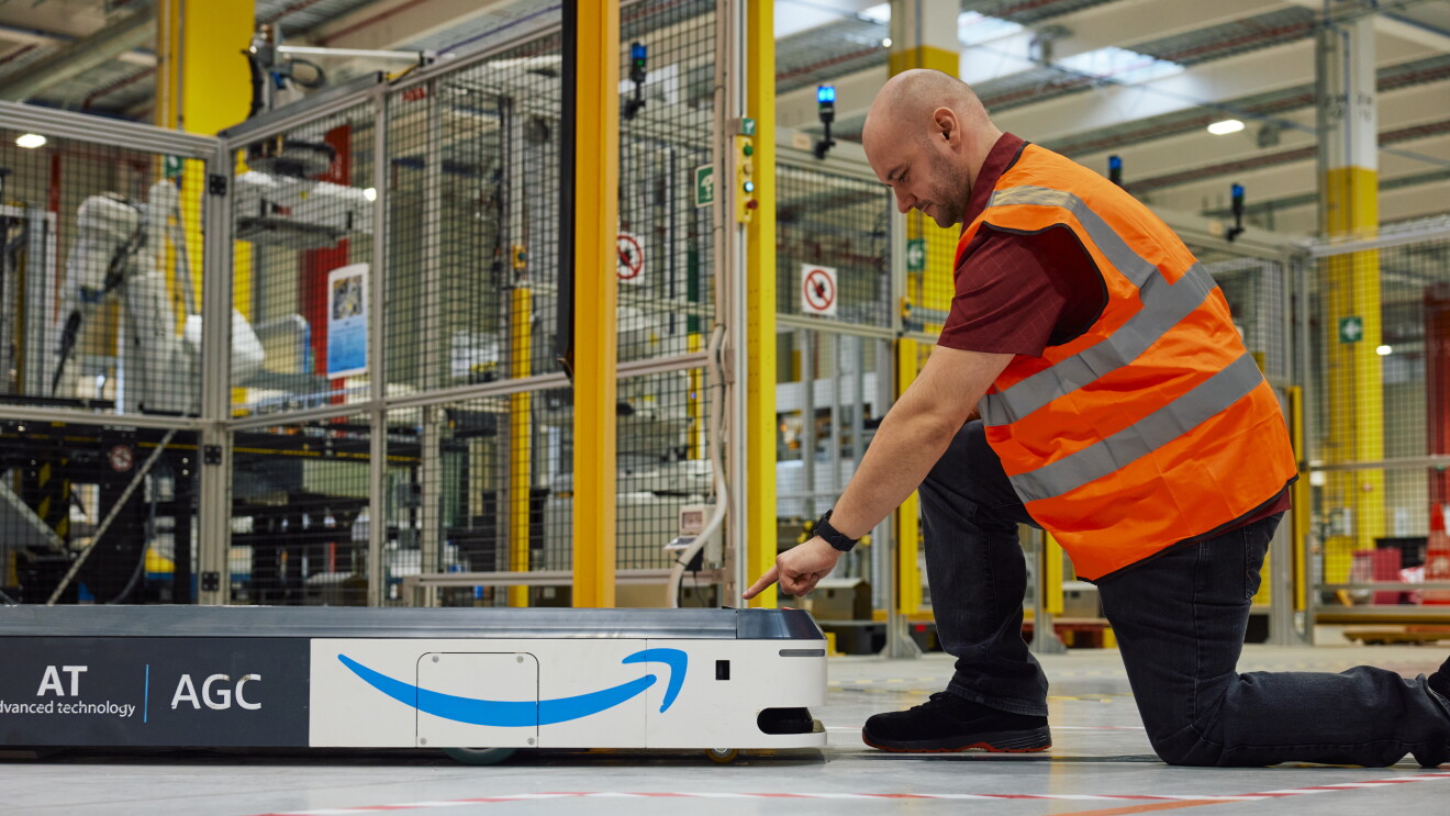 Trabajador de Amazon en un centro logístico de Amazon con un AGC.