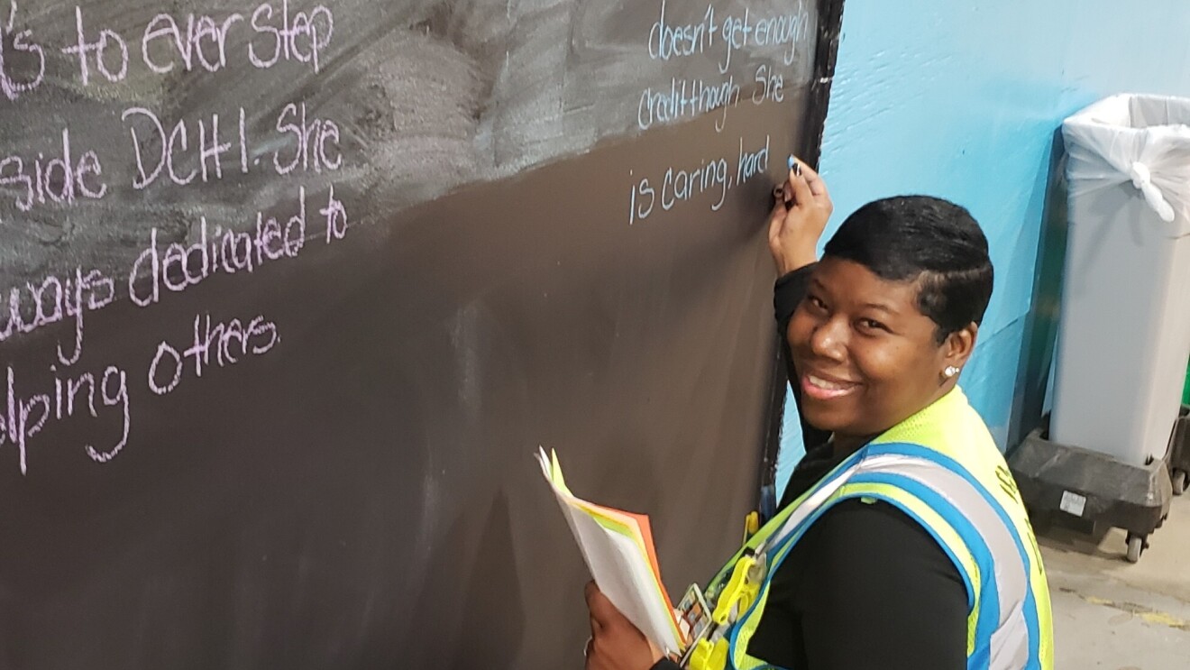 Amazon associate Tonisha Williams writes on a chalk board at an Amazon fulfillment center.