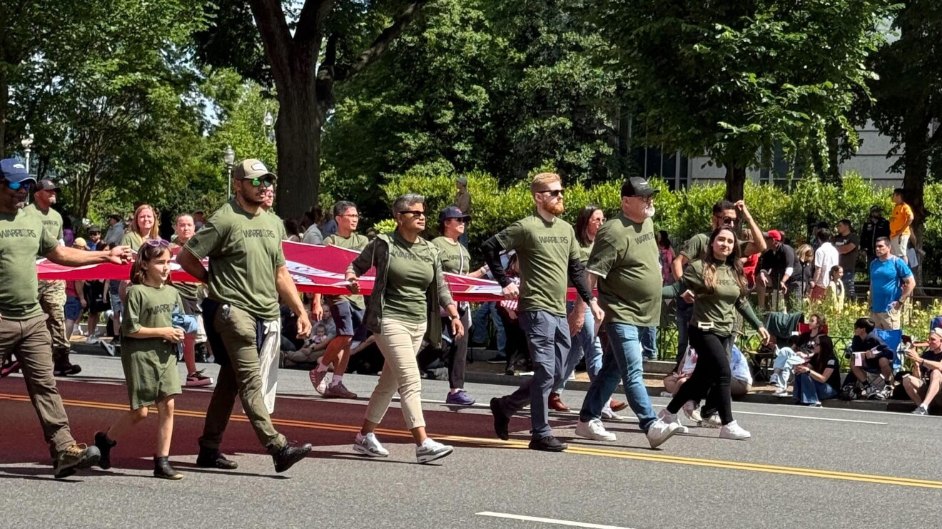 Veterans march in parade carrying American flags
