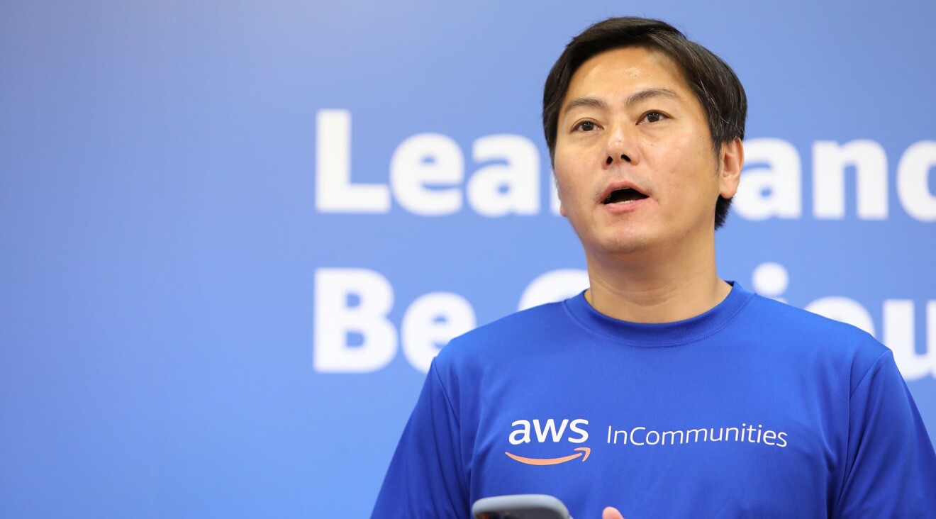 AWSのロゴが入った青いTシャツを着ている男性