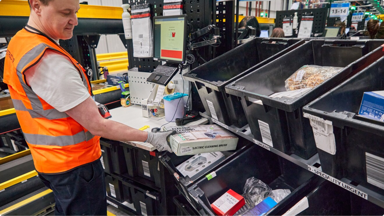 Amazon associate putting returned parcel in plastic sorting container