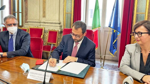 Il Ministro delle Politiche Agricole, Stefano Patuanelli, firma un protocollo di intesa con accanto Mariangela Marseglia. Alle sue spalle le bandiere dell'Italia e dell'Unione Europea