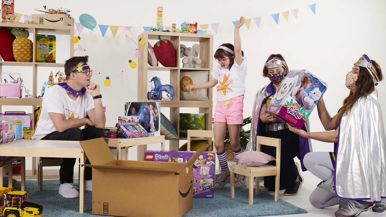 Children playing with toys from an Amazon box, Two volunteers sit near them and encourage their play. 