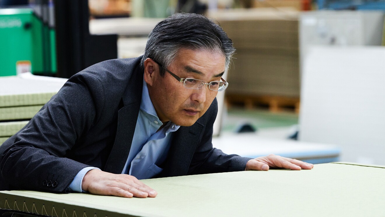 畳の表をじっと見つめるスーツを着た男性