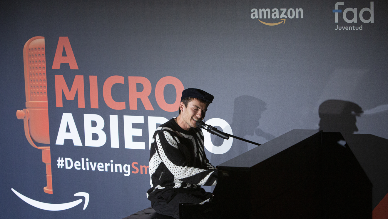Con el fondo de color azul con el logo de A micro abierto y la etiqueta Delivering Smile, el logo de Amazon y también el de Fundación FAD Juventud aparece Andrés Ceballos tocando un piano negro. Andrés Ceballos (antiguo vocalista de DVicio vestido con pantalón negro, jersey con estampado de zebra y gorra), está sentado en una banqueta y tocando el piano y cantando con un micro. 