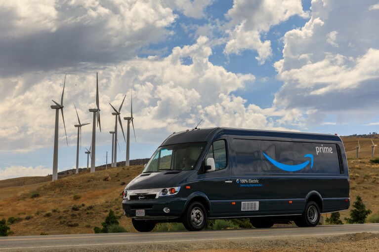 An Amazon truck drives past wind turbines
