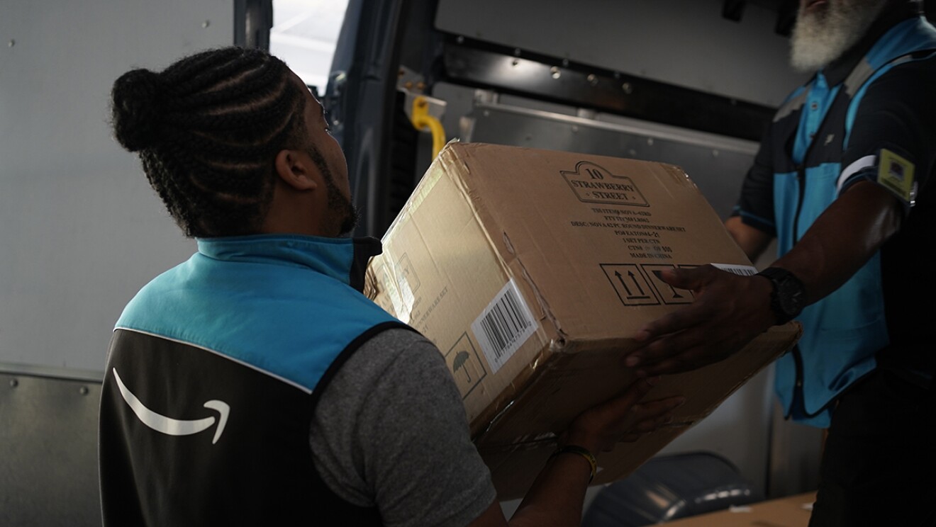Volunteers and Amazon employees load up Amazon delivery vans with essential furniture and household products.