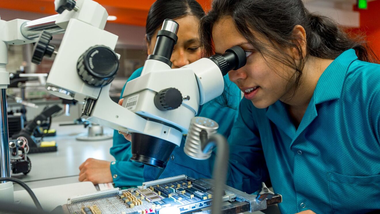 Amazon trainees view slides through a microscope as part of Project Kuiper.