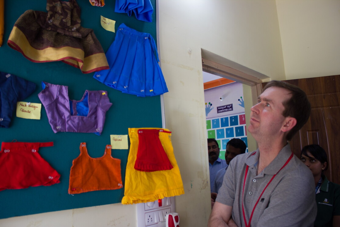 John Felton  looks at some clothes stitched by women at the Community Centres.