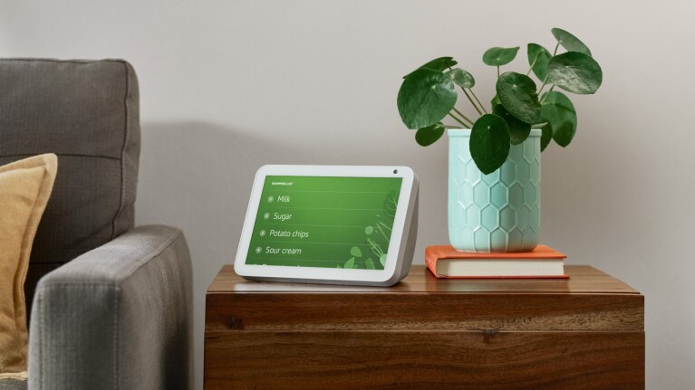 Smart display showing grocery list on wooden side table with plant