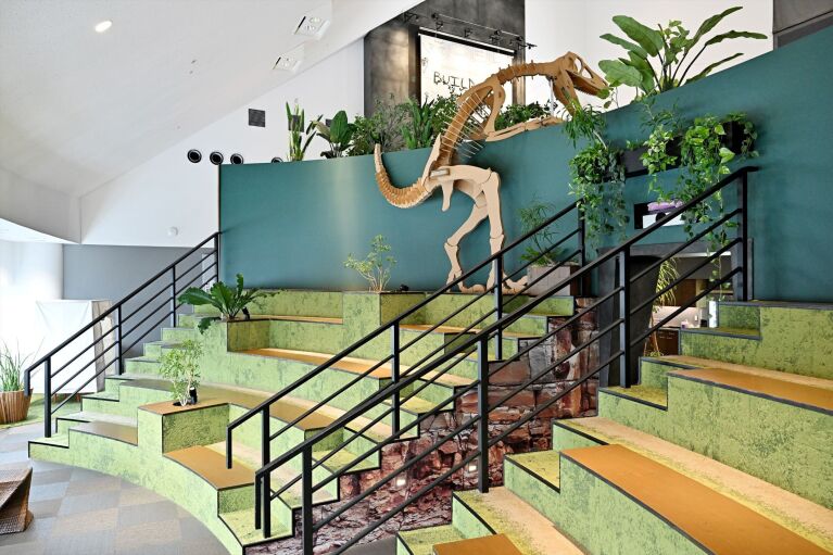 階段状になっている半円形シアター形式の座席の最上段に段ボールで作られた恐竜の骨格が置かれている