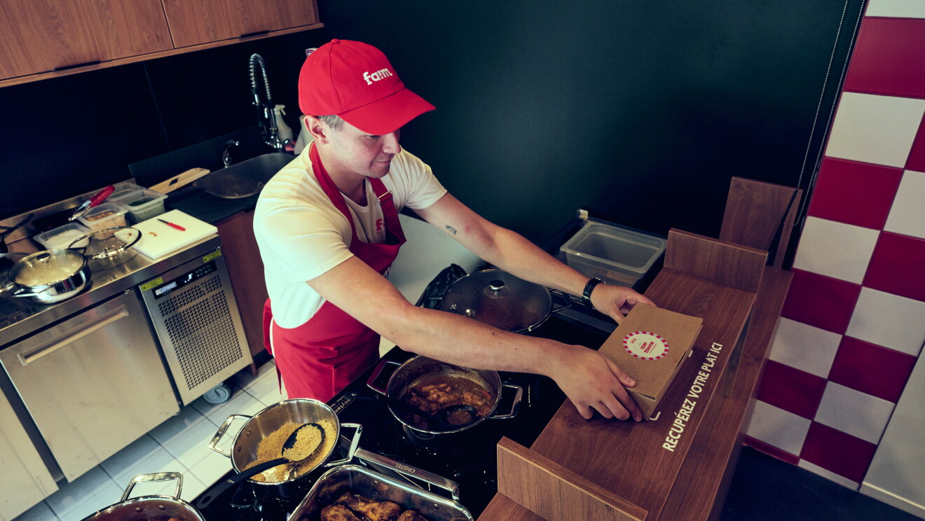 Employé portant une casquette rouge et un tablier, cuisinant au comptoir d'un petit restaurant