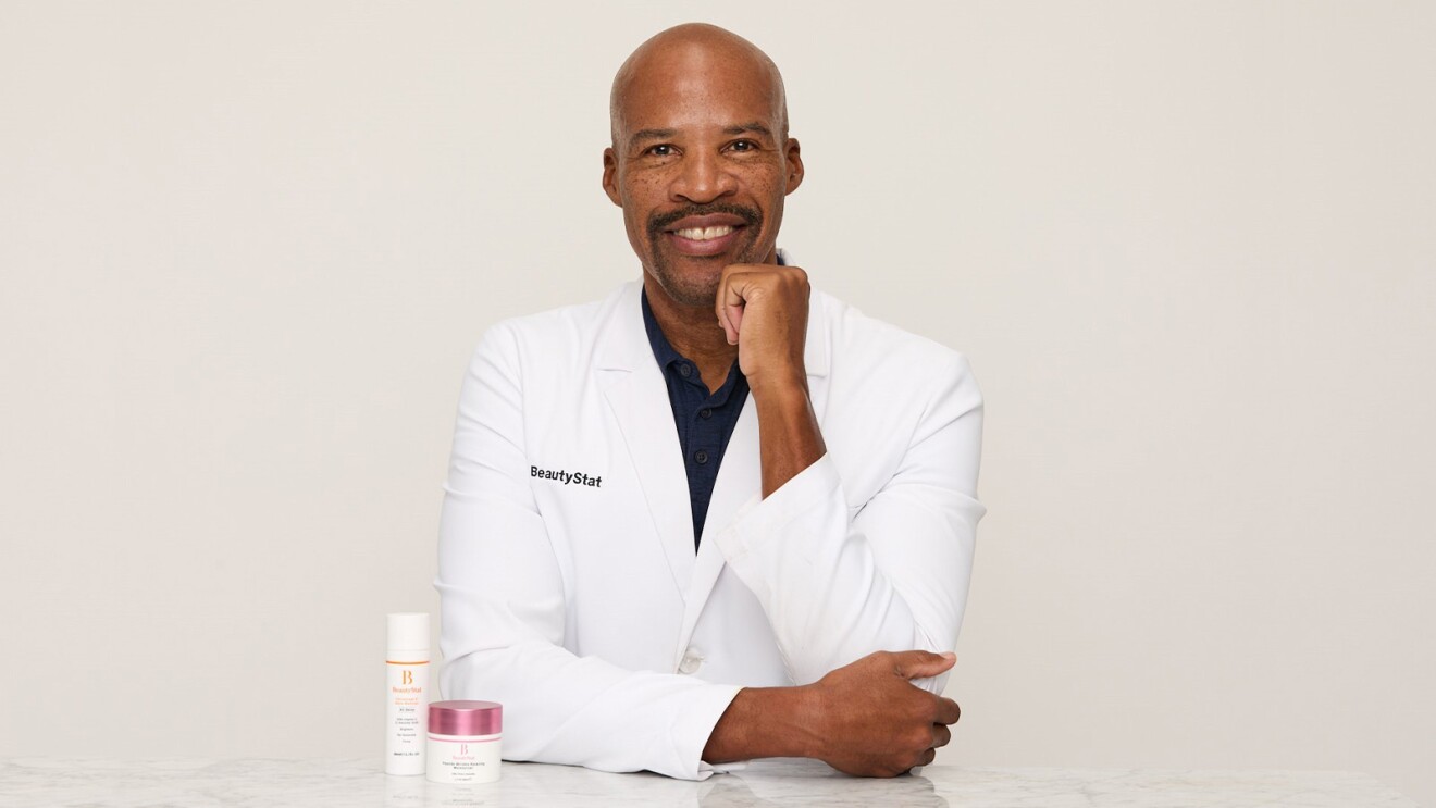 BeautyStat founder Ron Robinson poses in white lab coat with skincare products
