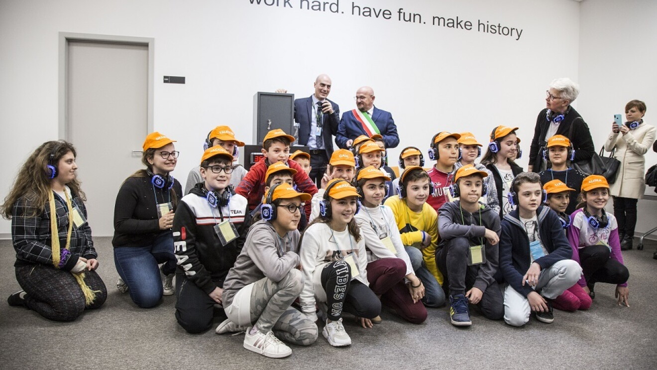 Bambini della scuola elementare seduti in terra con general manager Amazon e sindaco di Torrazza Piemonte per la cerimonia della capsula del tempo