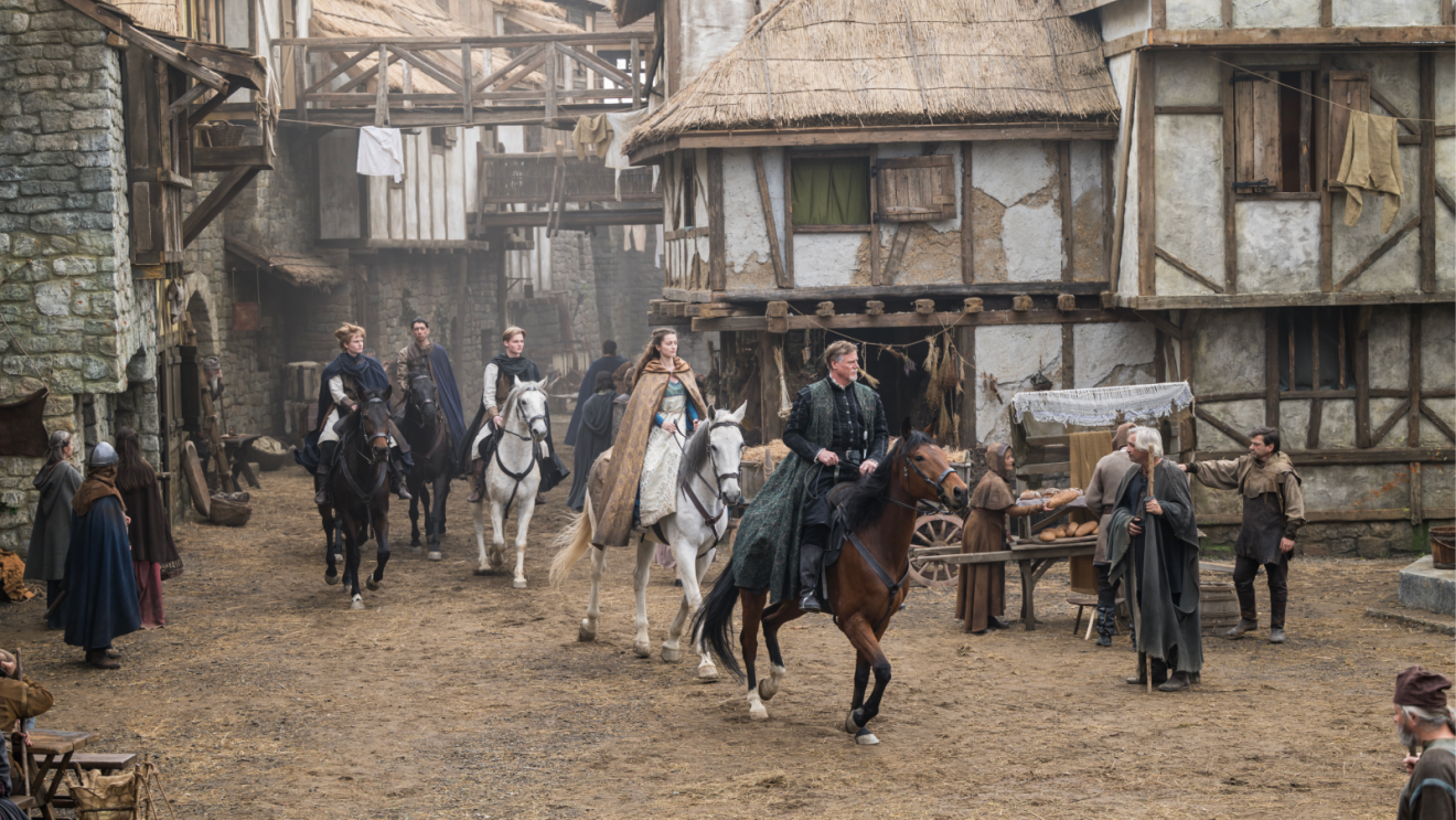 People on horseback riding through a medieval town while wearing period clothing