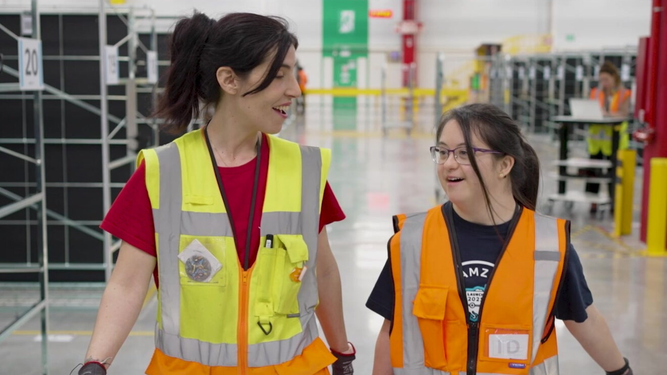 Dos trabajadoras de Amazon caminando por un centro logístico. 