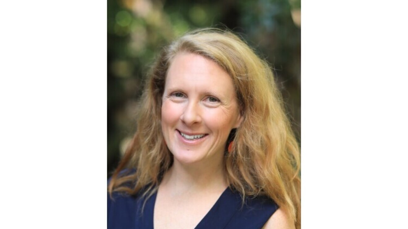 Dr. Annie Burgess, Lab Director, Earth Science Information Partners (ESIP). Sie hat dickes, blondes Haar mit einem Seitenscheitel, trägt ein dunkelblaues Oberteil und lächelt in die Kamera.