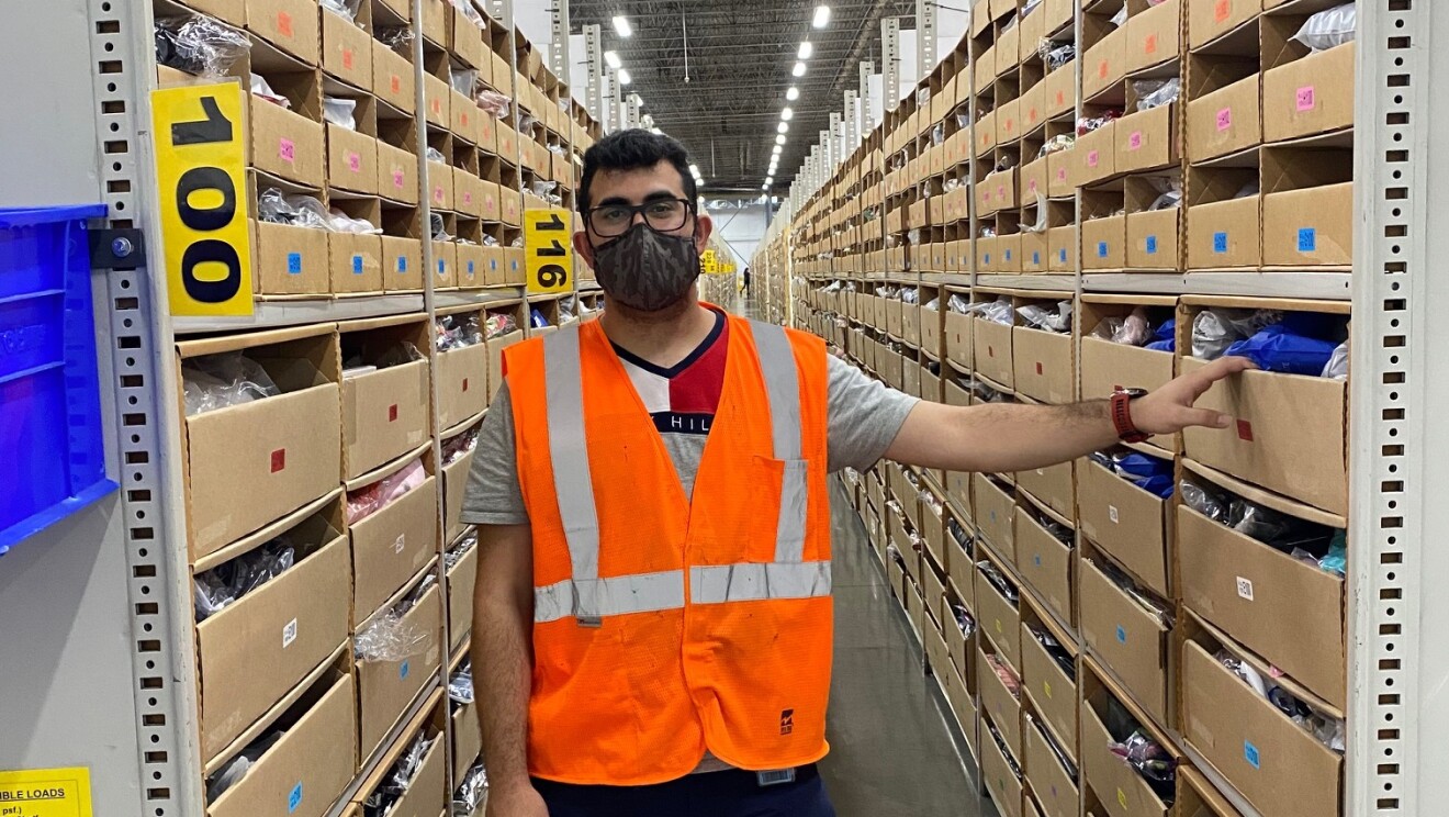 Shams Hussamy, an Amazon Associate, stands for a photo in the fulfillment center where he works in Ontario.