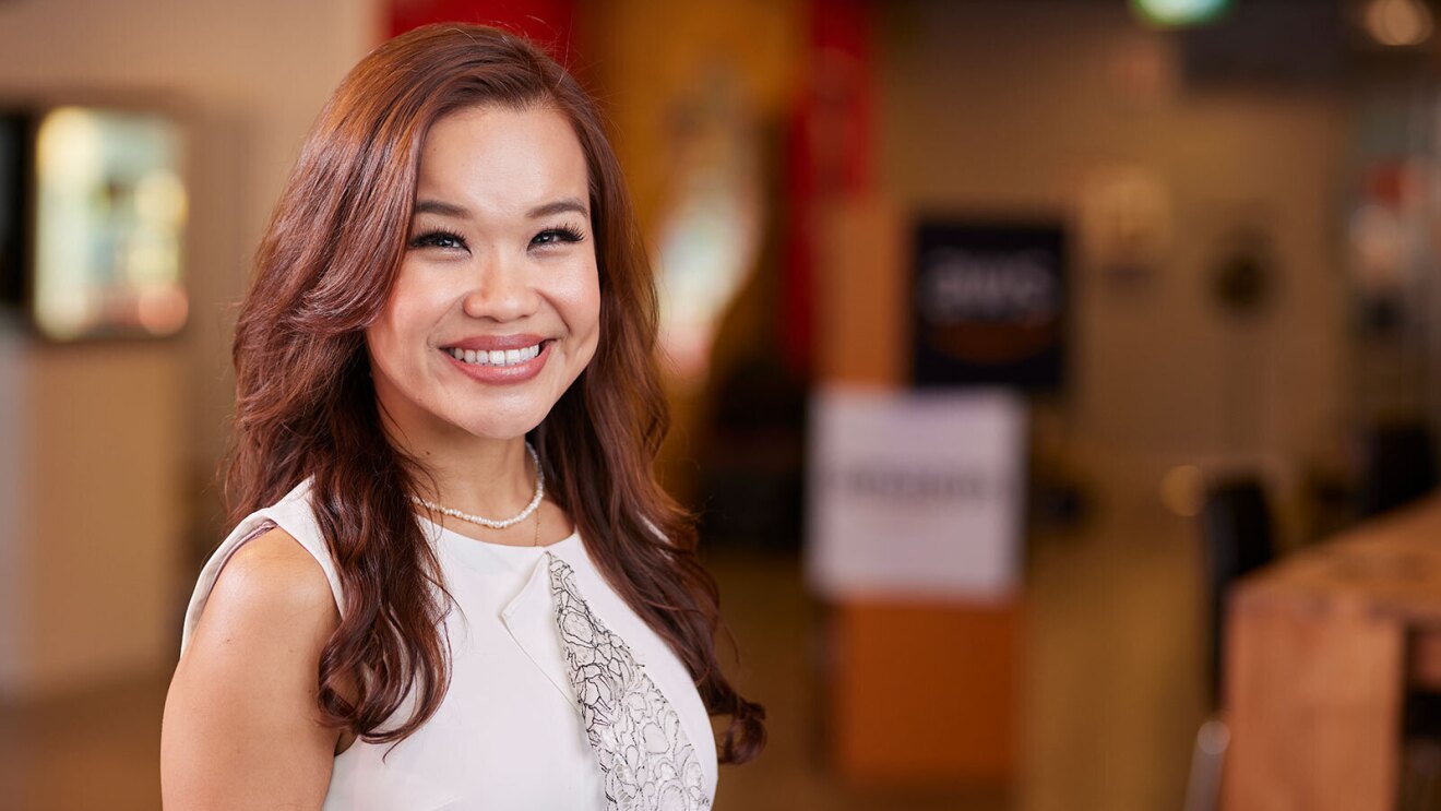 A headshot image of a woman smiling for a photo in the lobby of an Amazon office.