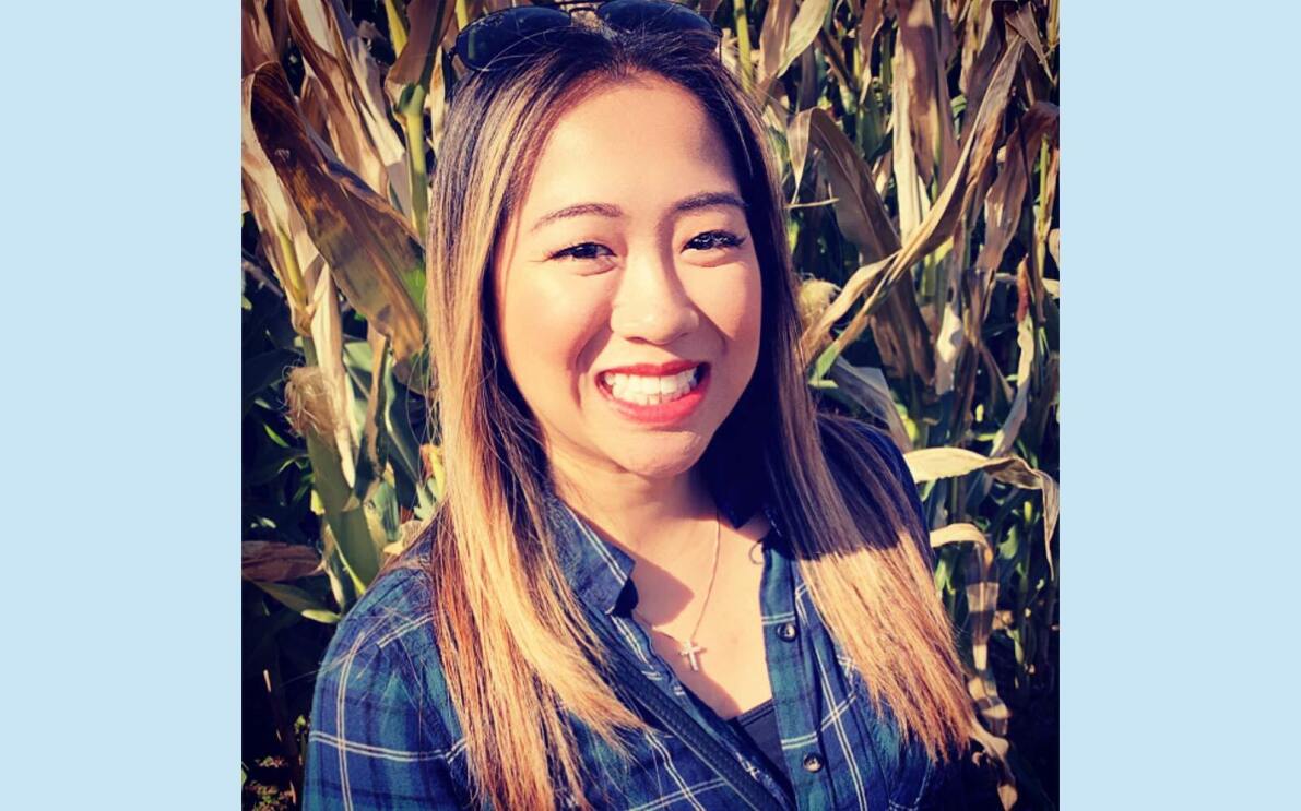 Amazon employee Robelynn stands in a corn field smiling at the camera. 