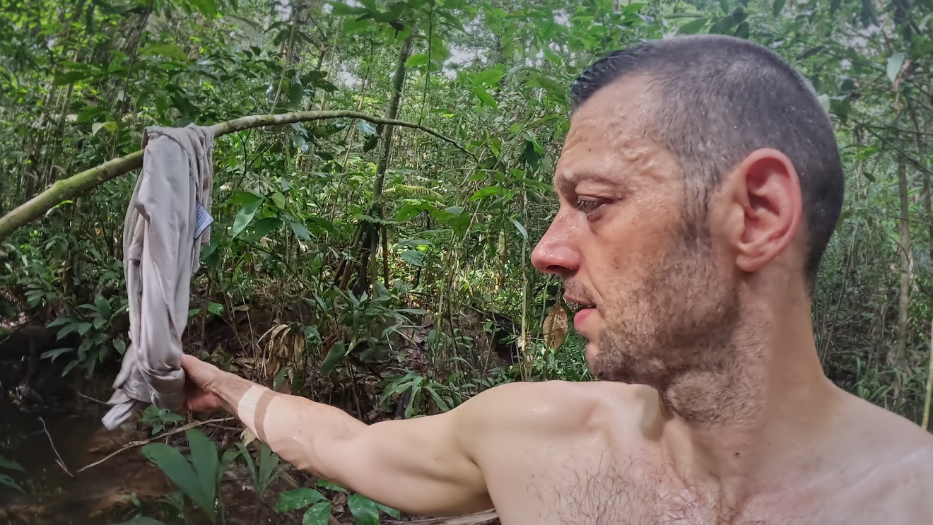 7 vs. Wild: Mann greift nach seinem nassen Tshirt was an einem Baum hängt