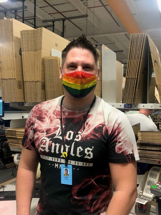Dean Barnes, an associate at Amazon's fulfilment centre in Durham, pictured at his packing station wearing a rainbow coloured face mask.