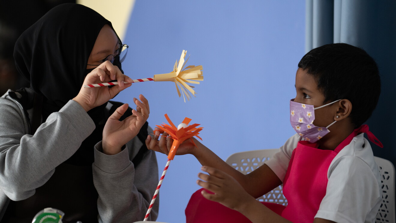 An older child creating artwork with a younger child