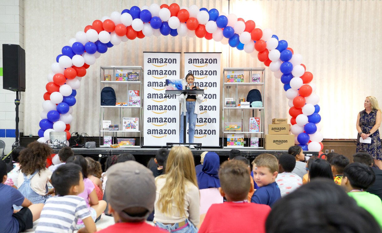 Suni Lee poses with students at an elementary school.