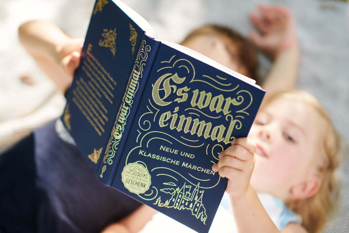 Zwei Kinder lesen zusammen in einem Märchenbuch