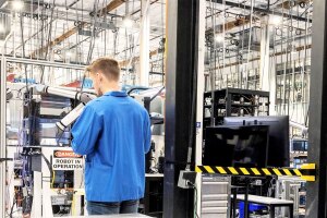 Amazon employee wearing blue lab coat working in a Project Kuiper factory. 