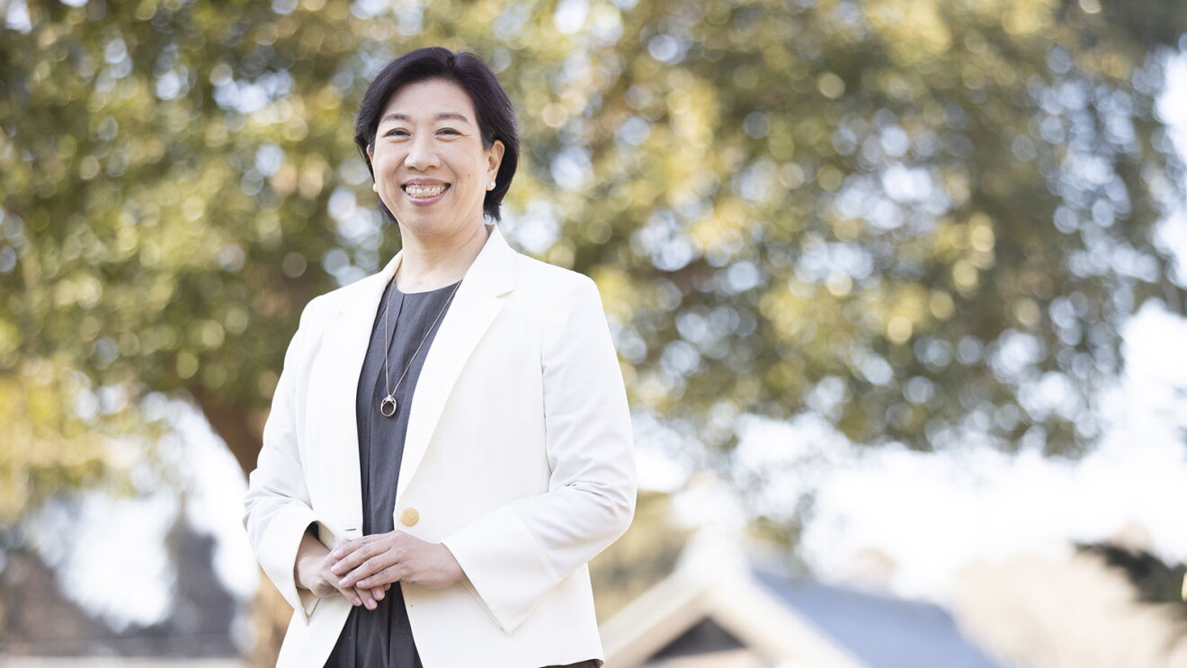 木の前に立つ、白いジャケット姿の鈴木さちよさん