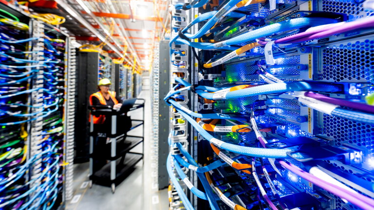 Amazon data center technician maintaining racks of networking equipment
