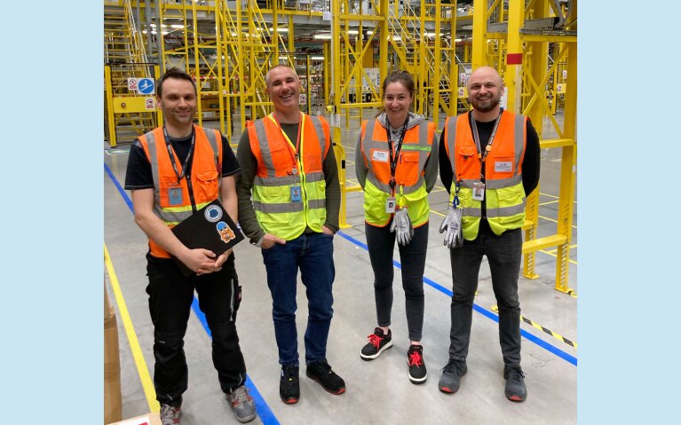 An image of Stefano Perego working with employees at an amazon facility.