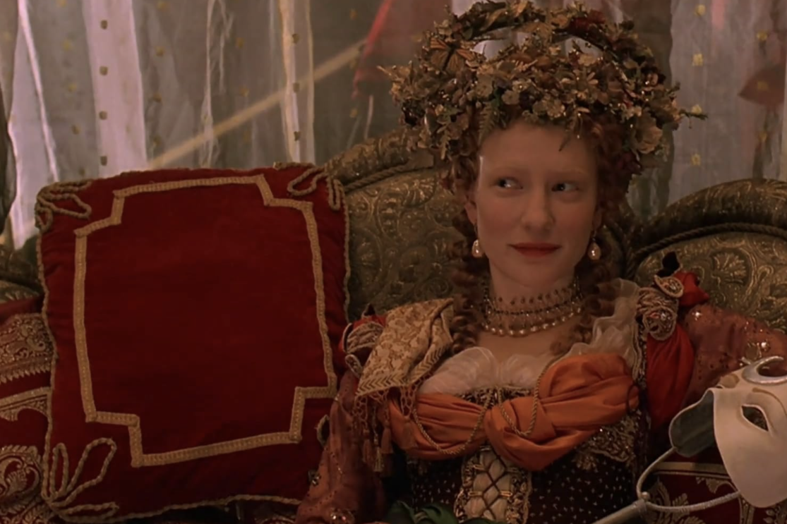 A woman in a costume sitting on a couch, showcasing her unique attire and relaxed posture.