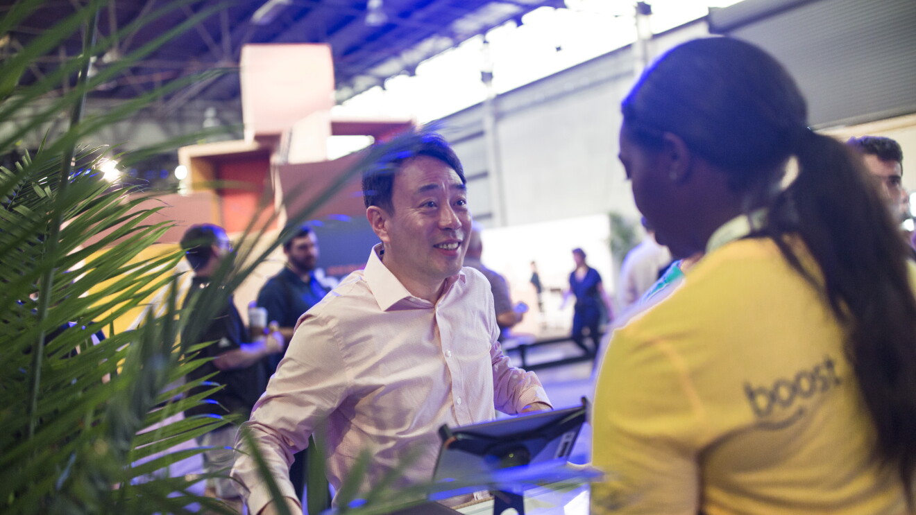 Small business owner talking to an Amazon associate at the Amazon Boost FBA conference. The Amazon employee is wearing a yellow t-shirt with "Boost" written on it. 