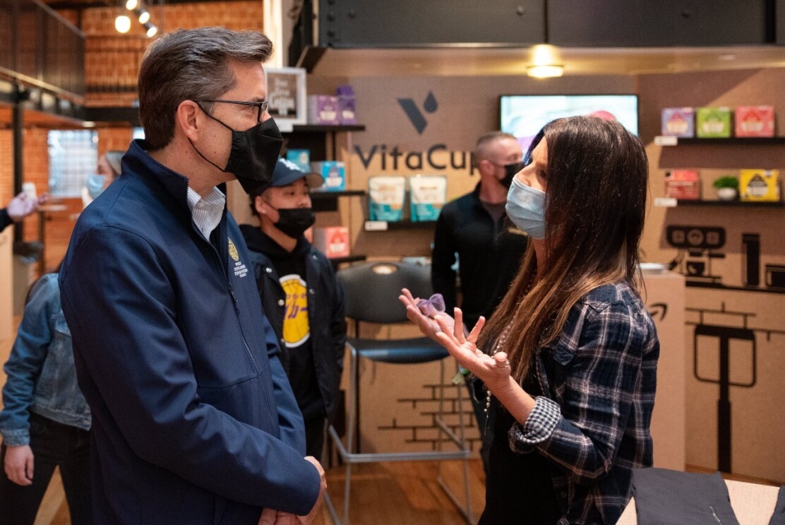 A woman wears a face mask while talking to a man wearing a face mask at the Shop Local event.