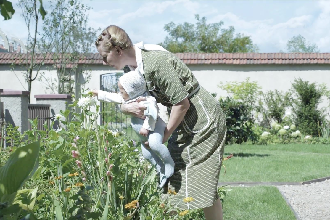 A woman holding a baby in a garden