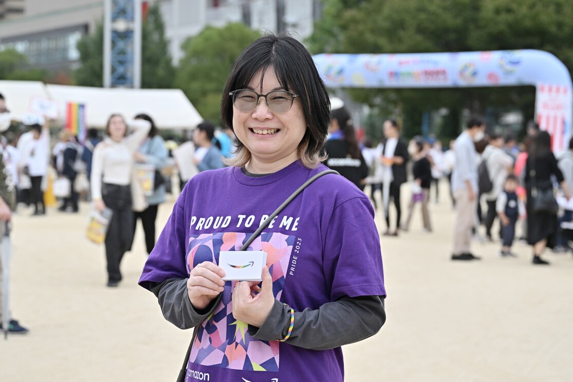 PROUD TO BE MEと書かれた紫色のTシャツを着た女性