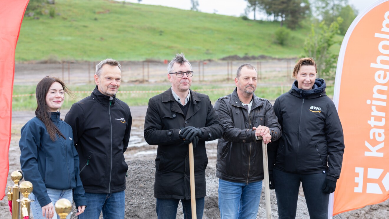 Team gathered at outdoor event with orange banner visible