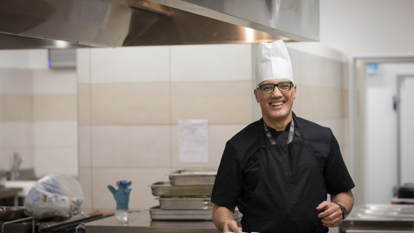 A chef holding a plate of food inside an Amazon fulfillment center in Italy.