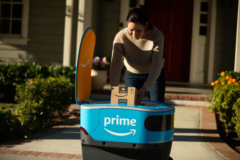 A woman retrieves her package from Scout in front of a home.
