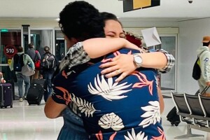 A photo of a former Afghan interpreter hugging their spouse in an airport.