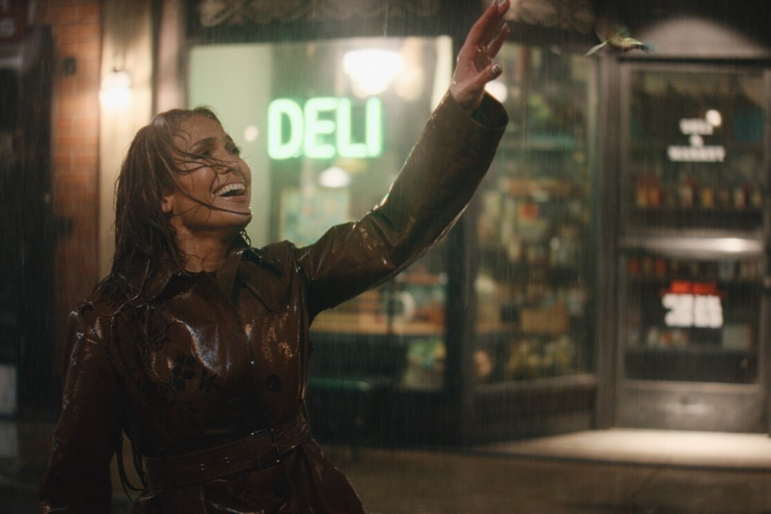 A woman smiling in the rain looking at a hummingbird