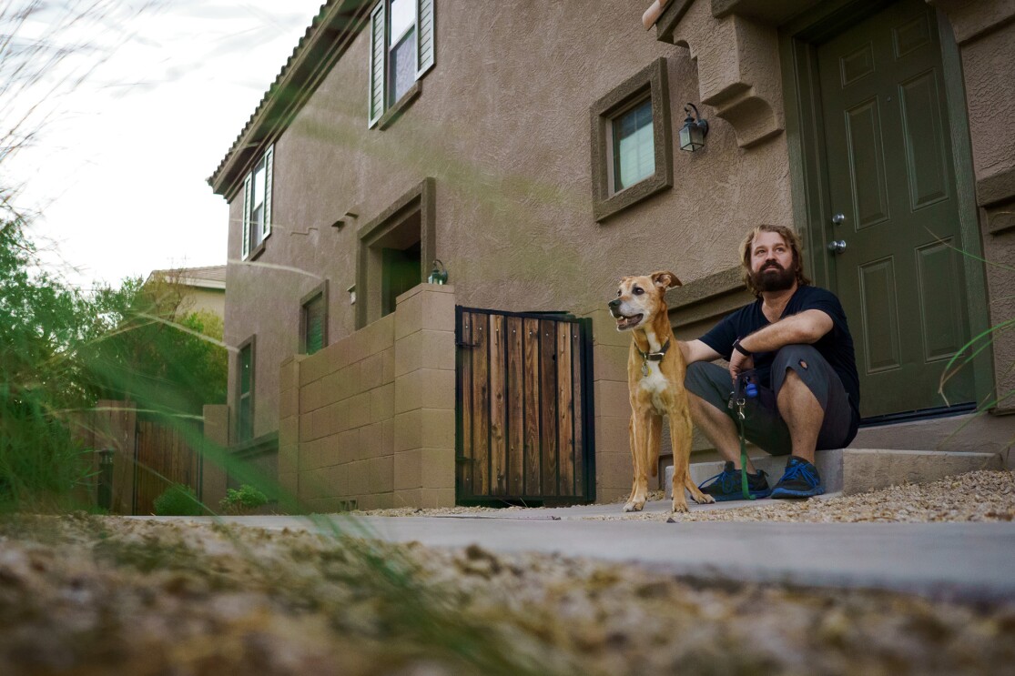 A dog and a man sitting on the doorstep of a home.