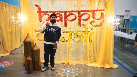 Nattan debout devant un panneau sur lequel est écrit « Joyeux Diwali »